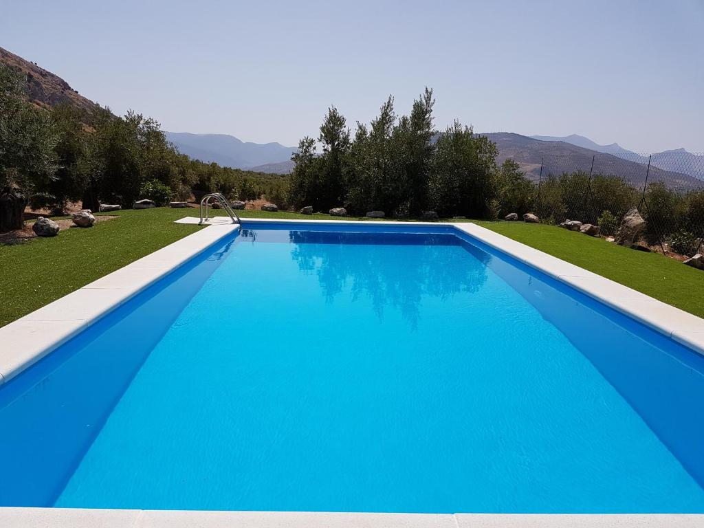 una gran piscina azul en un patio en Apartamentos Rurales La Dehesa del Acebuche, en Jaén