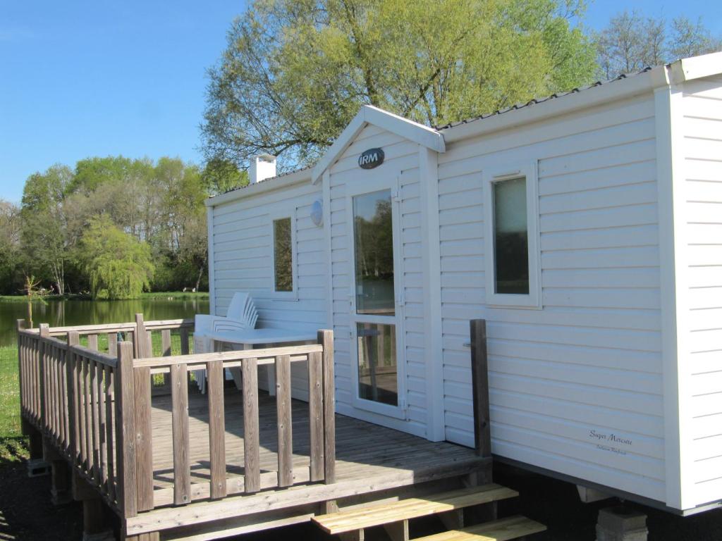 a white tiny house with a wooden deck at Camping du Mouchet in La Chapelle-Viviers