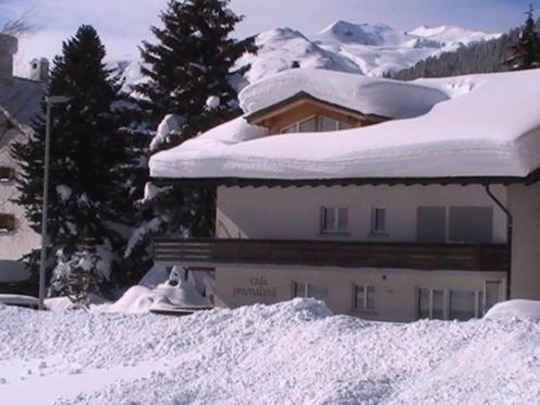 un edificio cubierto de nieve con árboles y montañas en Casa Pramalinis - Manstein, en Davos