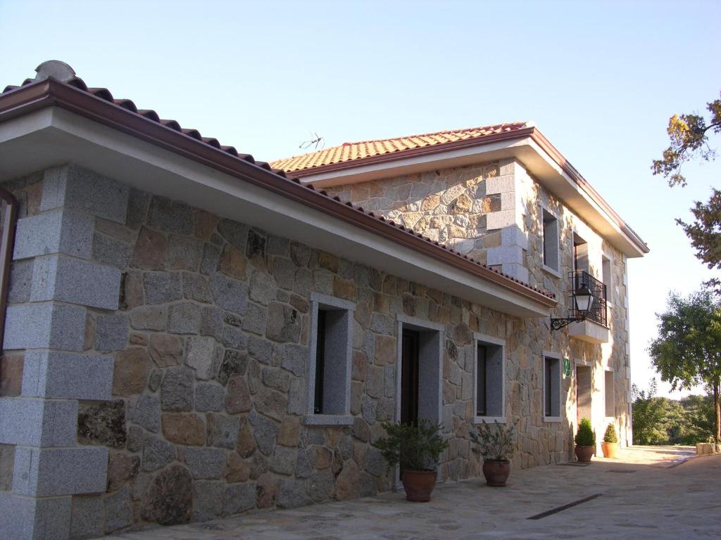 a stone building with windows and plants on it at Apartamento Rural Albus Albi in Colmenar del Arroyo