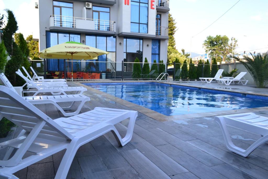 a swimming pool with chairs and an umbrella next to a building at Hotel Skyline Batumi in Batumi