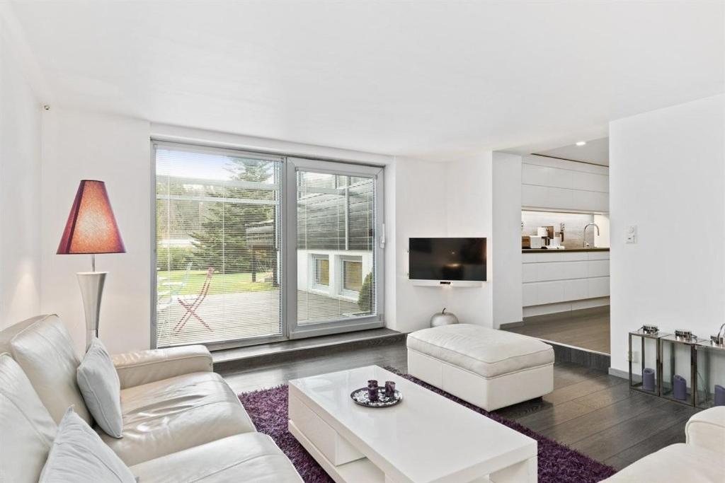 ein Wohnzimmer mit weißen Möbeln und einem großen Fenster in der Unterkunft Peak Apartments in Vossevangen