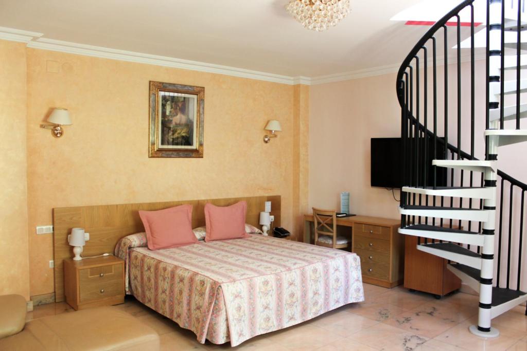 a bedroom with a bed with pink pillows and a staircase at Hotel Paraíso Del Mar in Nerja