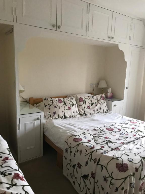 a small bedroom with a bed with a flowered blanket at Garstoncottage in Bath