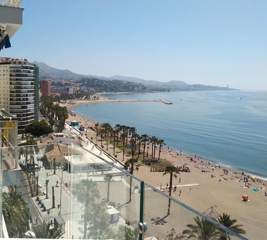 a view of a beach with palm trees and people at MALAGUETA BEACH in Málaga