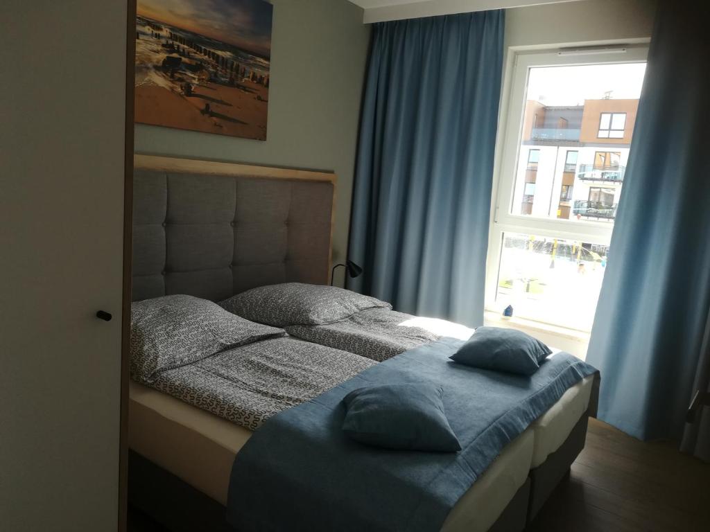 sypialnia z łóżkiem z poduszkami i oknem w obiekcie Bel Mare Patio B217 w mieście Międzyzdroje