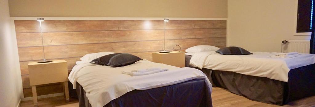 een kamer met 2 bedden en een houten muur bij Hotelli Haapajärvi in Haapajärvi
