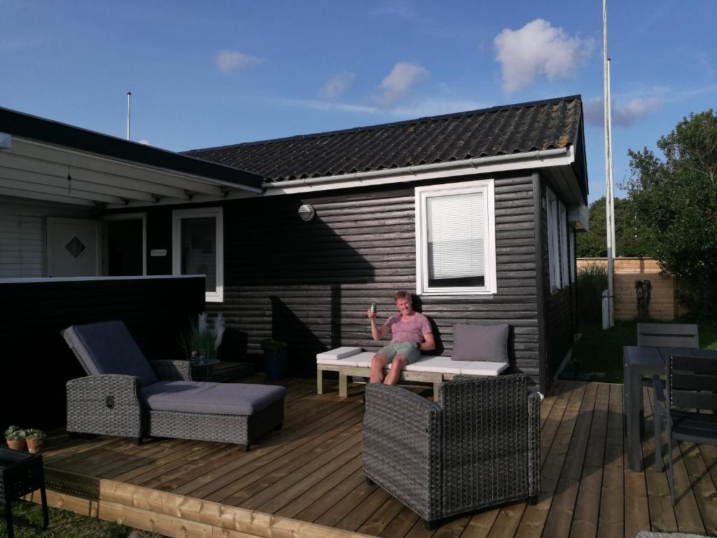 a woman sitting on a deck in front of a house at The Beach House in Haderslev