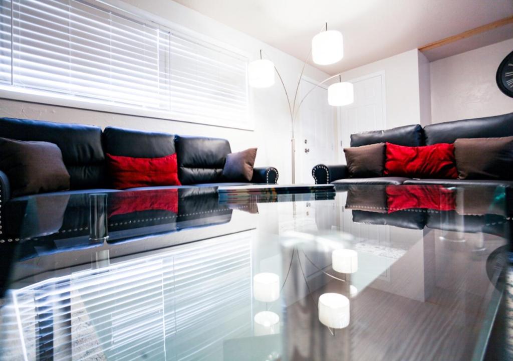 sala de estar con sofás de cuero negro y mesa de cristal en The Diamond at Kingston East, en Rexburg
