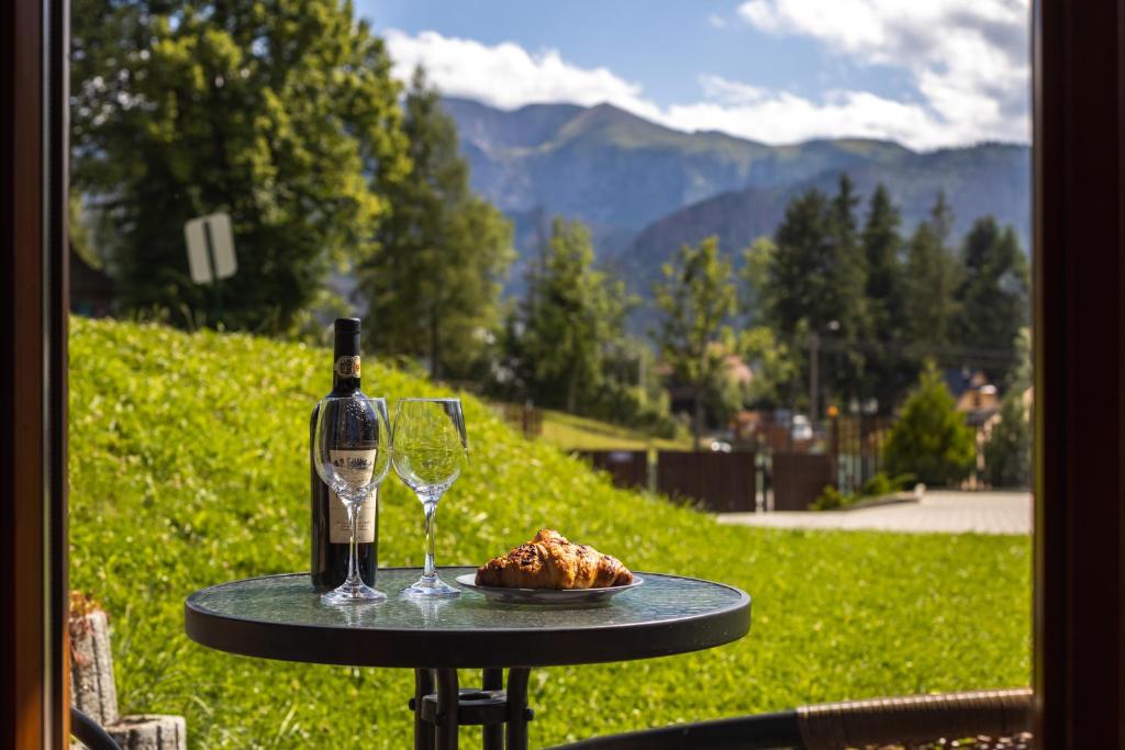 a table with a bottle of wine and a plate of food at Apartament Południowy z widokiem- sauna, jacuzzi, kominek in Kościelisko