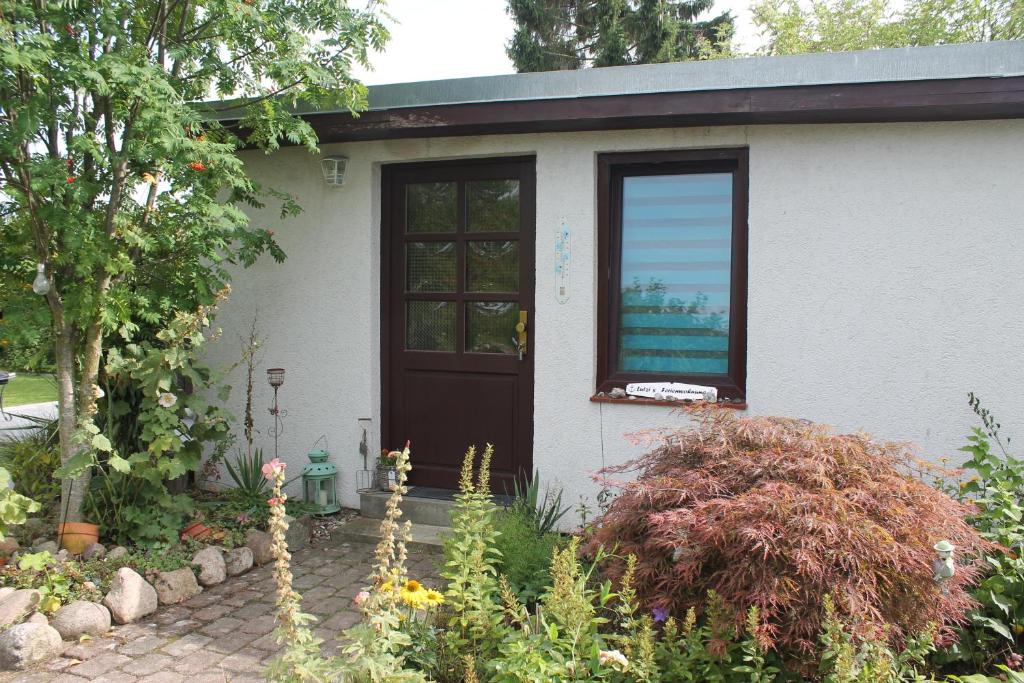 una pequeña casa blanca con puerta y ventana en Lutzi´s Ferienwohnung en Rostock