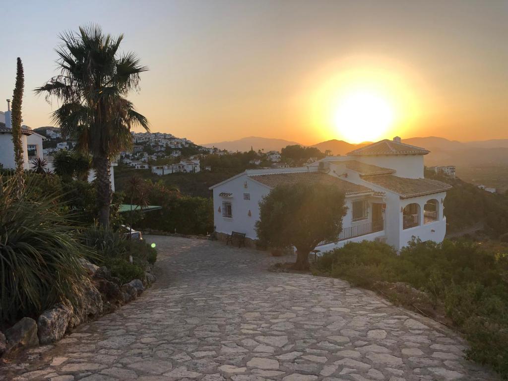 una casa en una colina con la puesta de sol en el fondo en El Valle Verde en Monte Pego