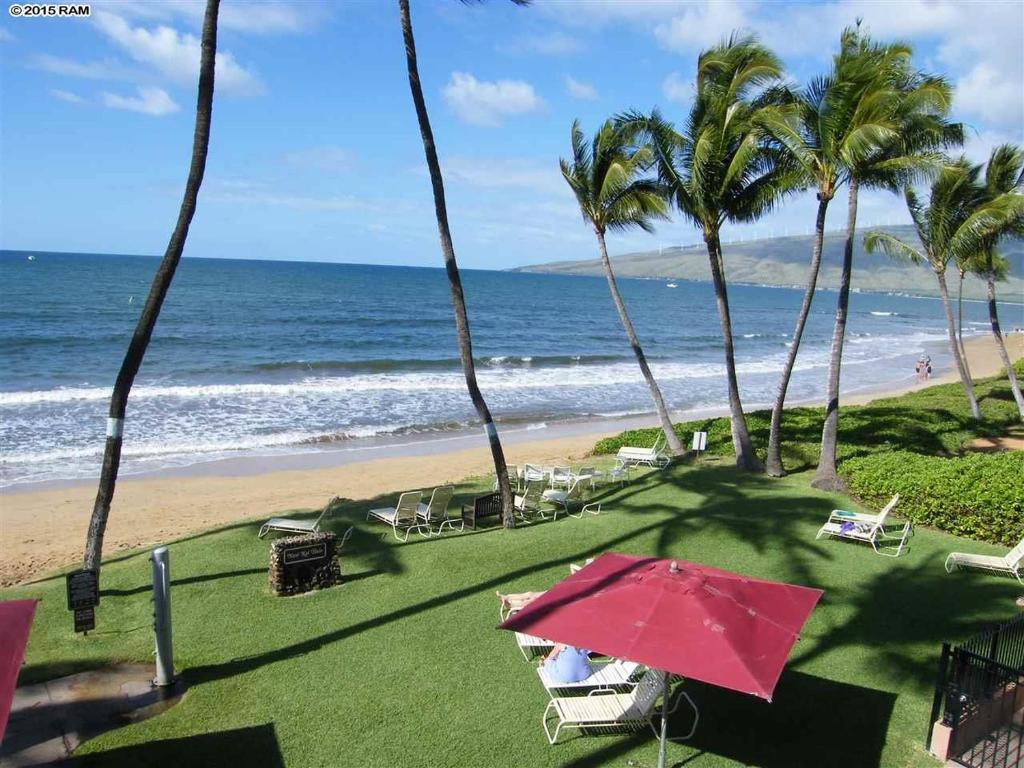 a beach with palm trees and a red umbrella at Nani Kai Hale in Kihei