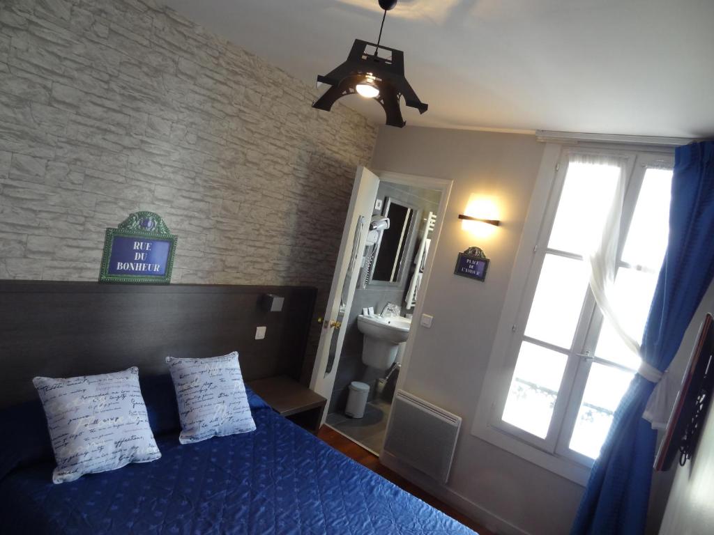 a bedroom with a blue bed and a window and a sink at Amélie Hotel in Paris