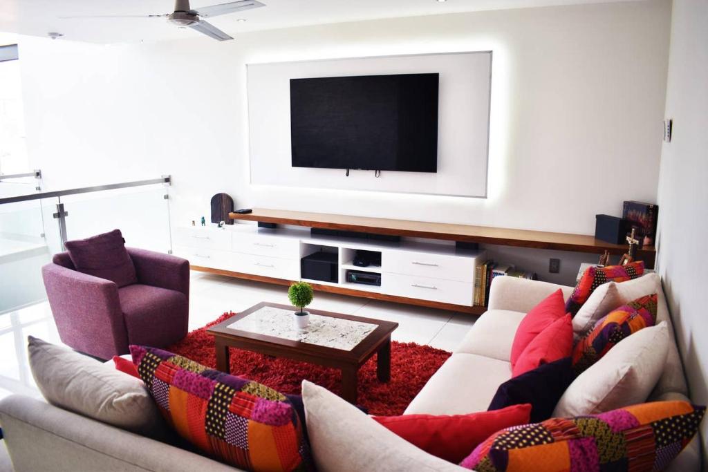 sala de estar con sofá y TV de pantalla plana en En la Feria Penthouse Lujo AC WiFi 300mbps, en Aguascalientes