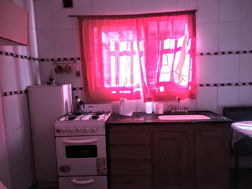 eine Küche mit einem rosa Fenster, einem Herd und einer Spüle in der Unterkunft Mate de luna in Buenos Aires