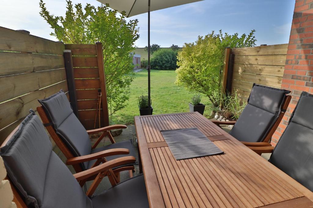 um pátio com uma mesa de madeira e cadeiras em Freundliche Ferienwohnung direkt hinter dem Deich em Friedrichskoog