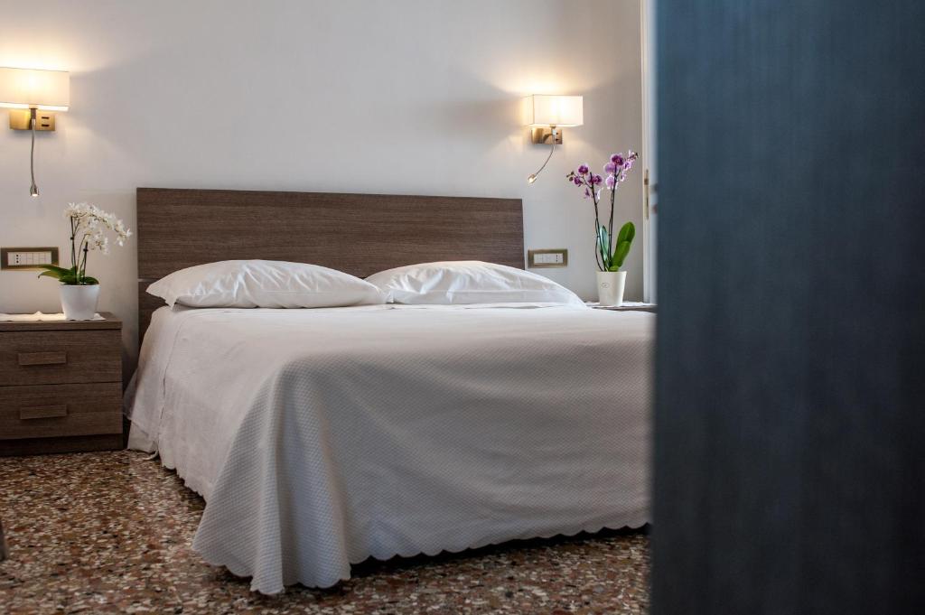 - une chambre avec un lit doté de draps et d'oreillers blancs dans l'établissement Ca' Dorè, à Venise