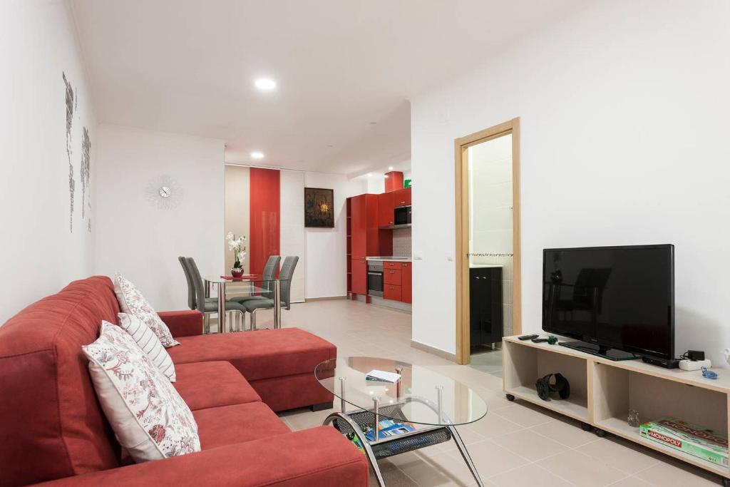 uma sala de estar com um sofá vermelho e uma televisão em Apart Baía do Sado II em Setúbal