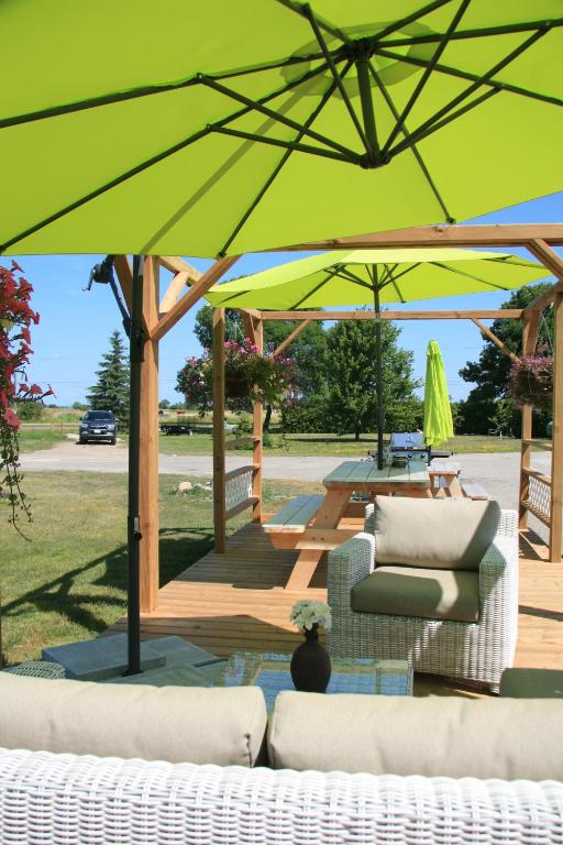 a patio with two couches and a large green umbrella at Wayside Motel Manitoulin in Manitowaning
