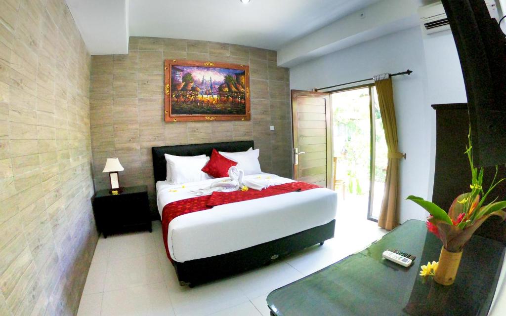 1 dormitorio con 1 cama blanca grande con almohadas rojas en Palm Bamboo Hotel en Nusa Dua