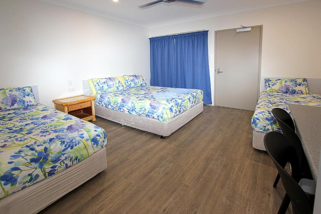 a hotel room with two beds and a table at Reef Gardens Motel in Proserpine