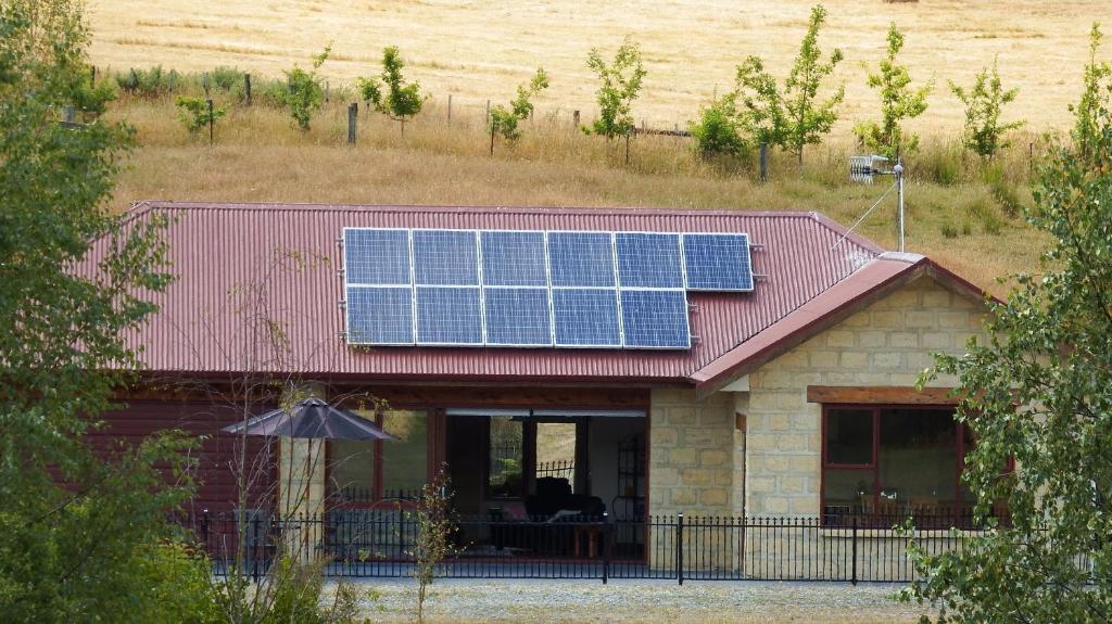 ein Haus mit einem Dach mit Sonnenkollektoren darauf in der Unterkunft Mahana Farm Cottage in Mahana