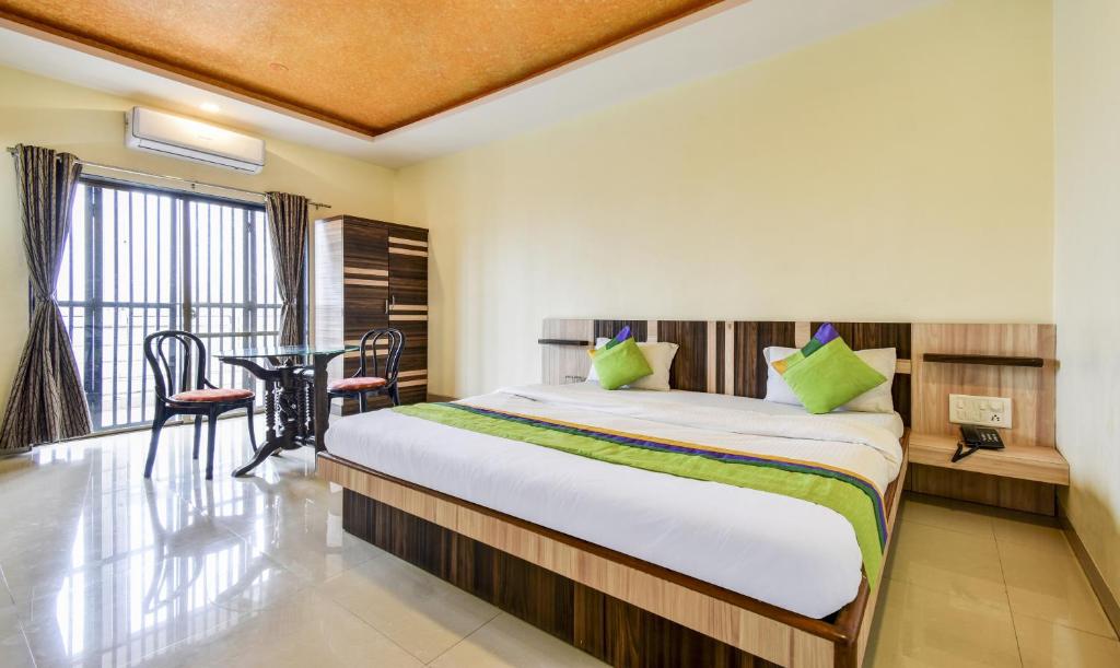 a bedroom with a bed and a table and a window at Gugal Residency Mahabaleshwar in Mahabaleshwar