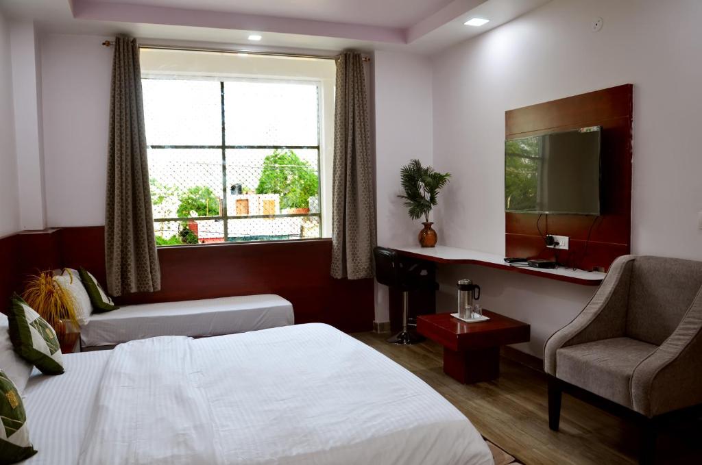 um quarto de hotel com uma cama e uma cadeira e uma janela em Meera Mahal em Sawai Madhopur