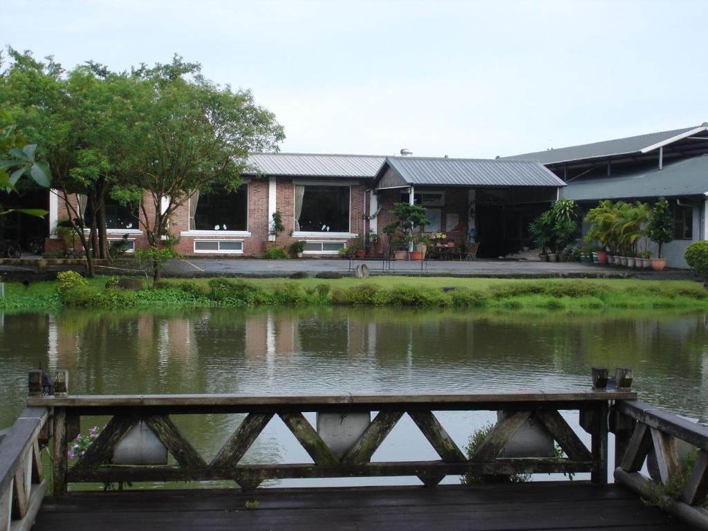 un pont sur un étang en face d'un bâtiment dans l'établissement Homeinn, à Meinong