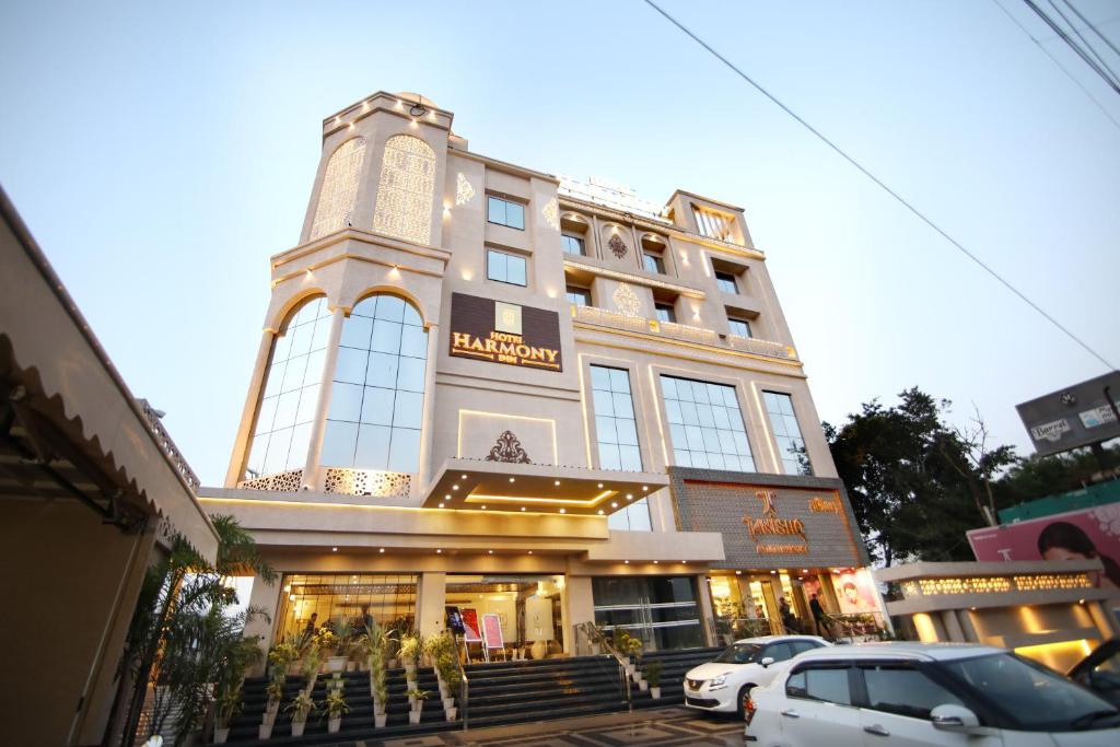 ein hohes Gebäude mit davor geparkt in der Unterkunft Hotel Harmony Inn in Meerut