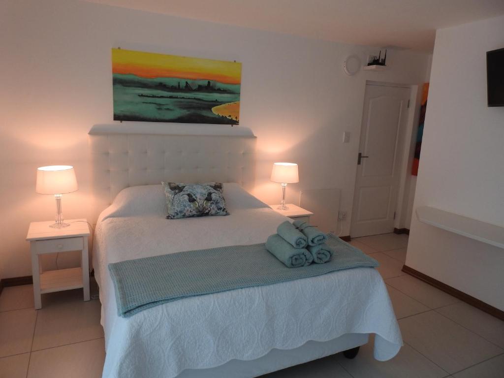 a bedroom with a white bed with two lamps at Berg en Dal Accommodation in Saldanha