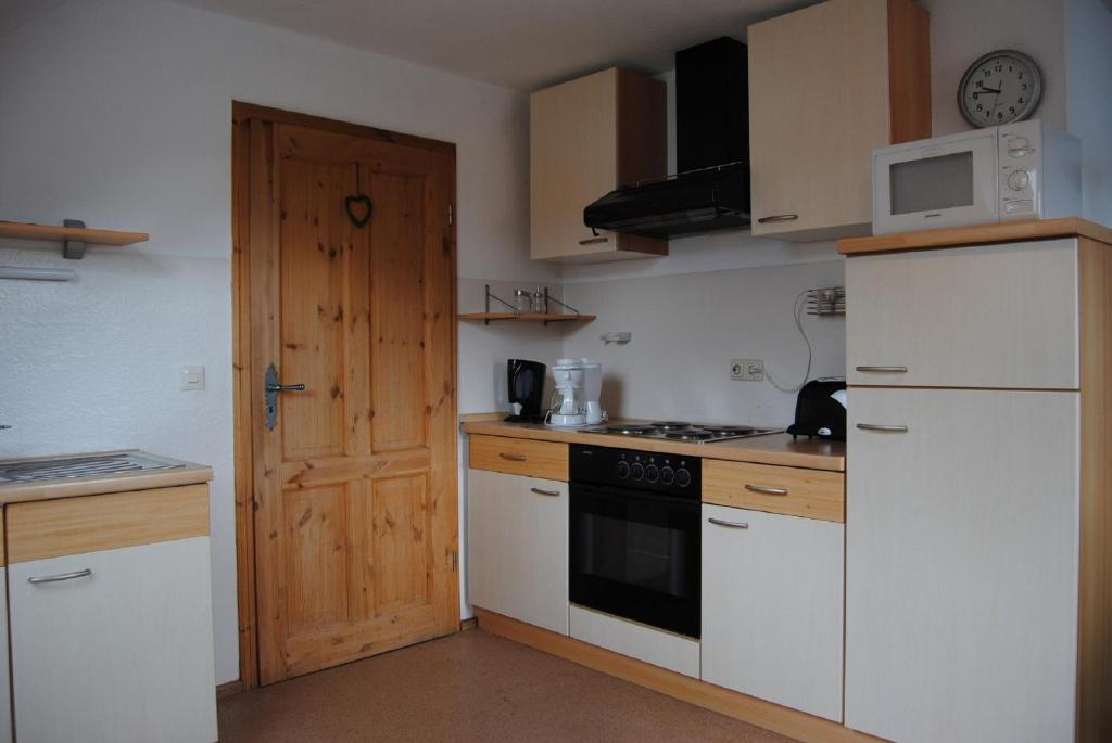 uma cozinha com electrodomésticos brancos e uma porta de madeira em Haus Wiesengrund em Rauhenebrach