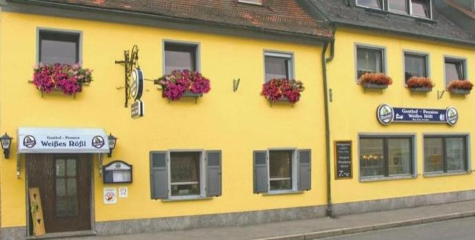un edificio amarillo con ventanas y cajas de flores. en Gasthof Pension Weißes Rössl, en Floß