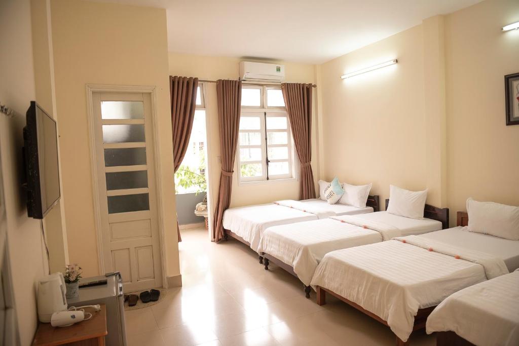 a bedroom with three beds and a window at Minh Tam Guesthouse in Hue