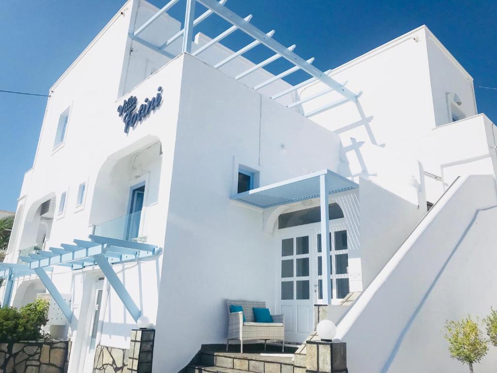 a white house with blue stairs and chairs at Villa Fotini in Firostefani