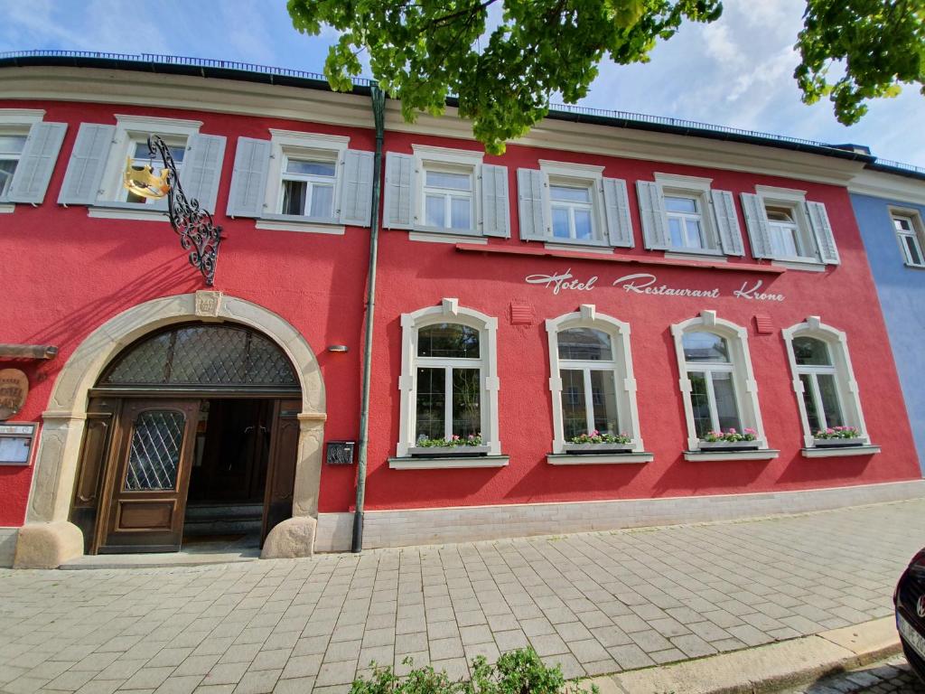 a red building with a flag in front of it at Hotel & Restaurant Krone in Rehau