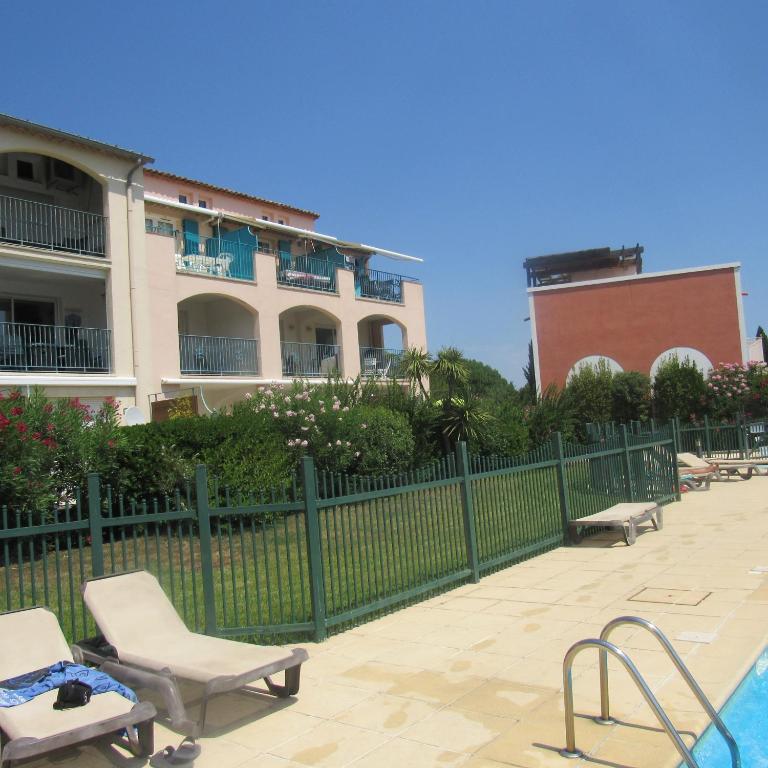 un bâtiment avec une piscine et une chaise à côté d'une clôture dans l'établissement Résidence les Grimaudières, à Grimaud