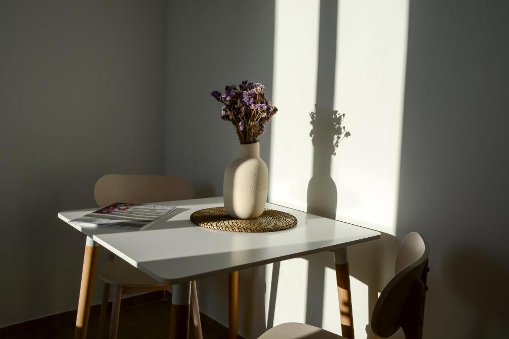 a table with a white vase with flowers in it at Pharos Apartments in Gavrio