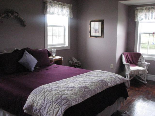 a bedroom with a purple bed and two windows at Argyle By The Sea Bed & Breakfast in Pubnico