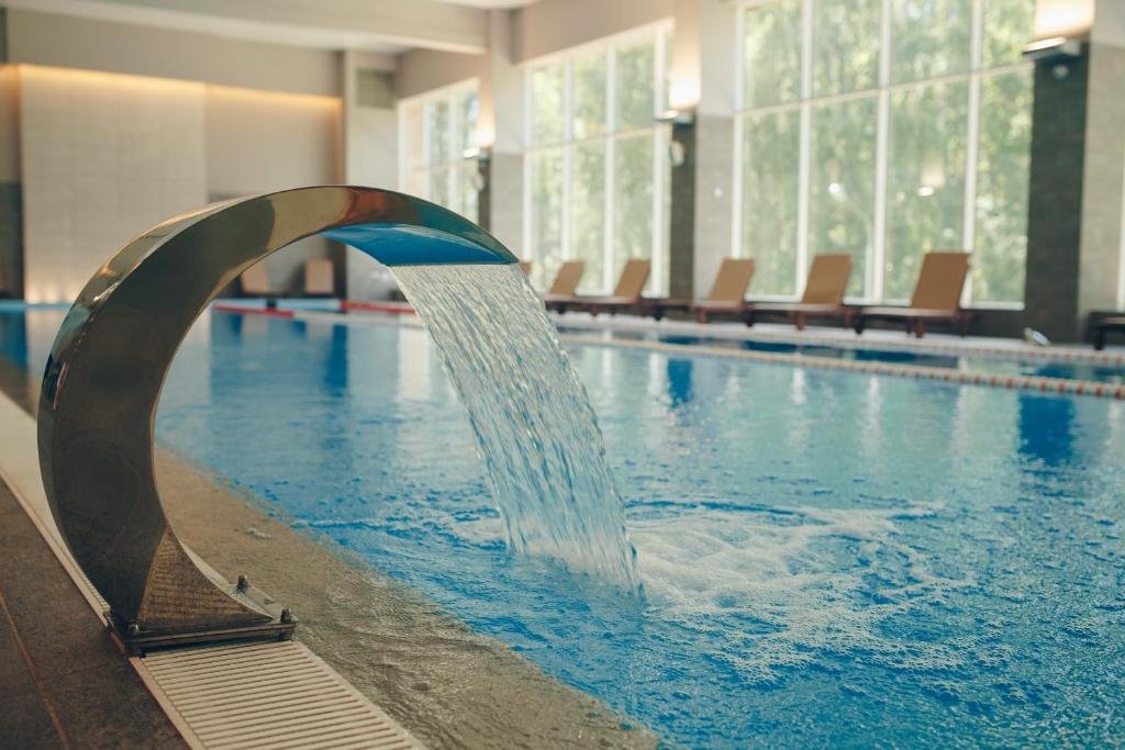 a swimming pool with a water fountain in a building at Daina Jurmala Beach Hotel in Jūrmala