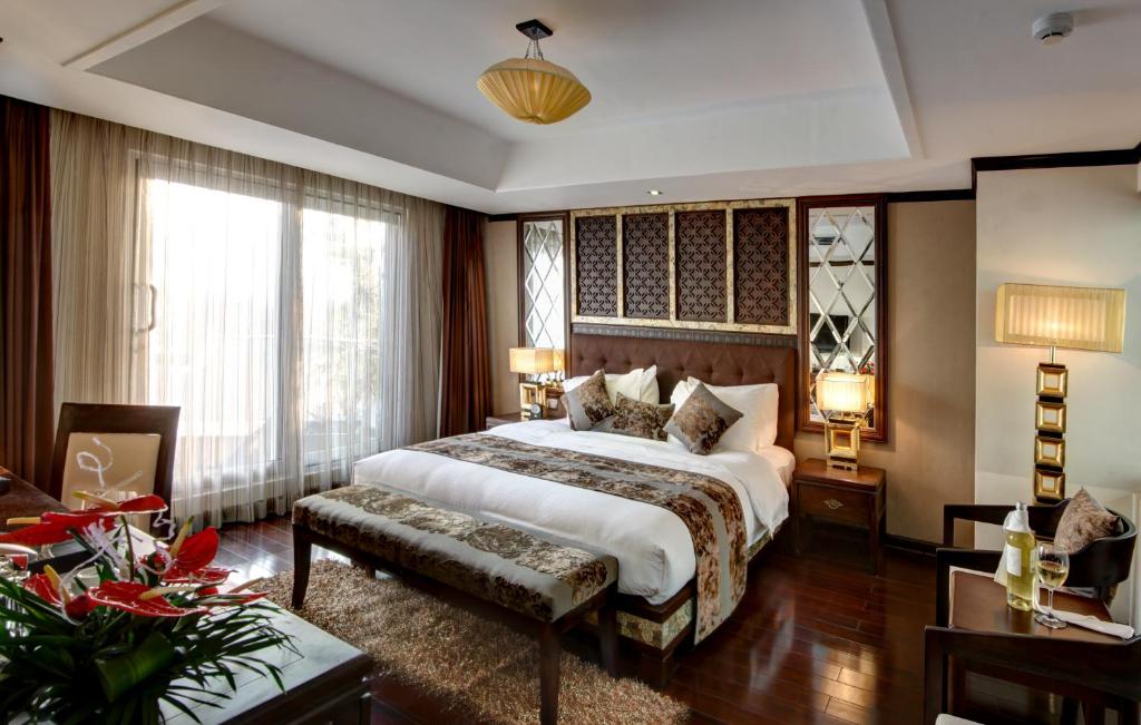a bedroom with a king sized bed and a table at Golden Lotus Luxury Hotel in Hanoi