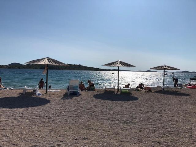 a group of people sitting on a beach with umbrellas at Apartman Sena in Vodice