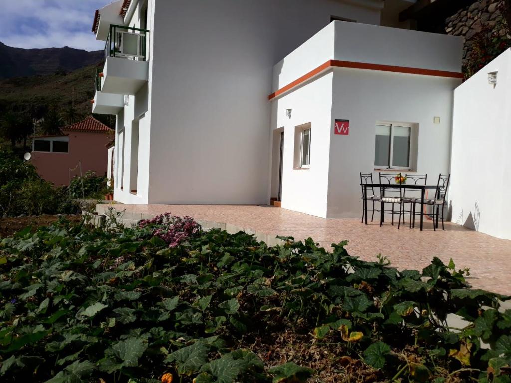 a garden in front of a white building with a table at Vivienda Casa Mary in Valle Gran Rey