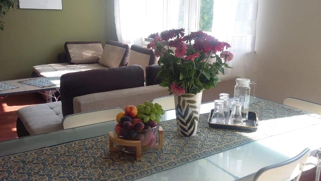 uma mesa com um vaso de flores e uma taça de fruta em Apartment Leśniczówka em Radom