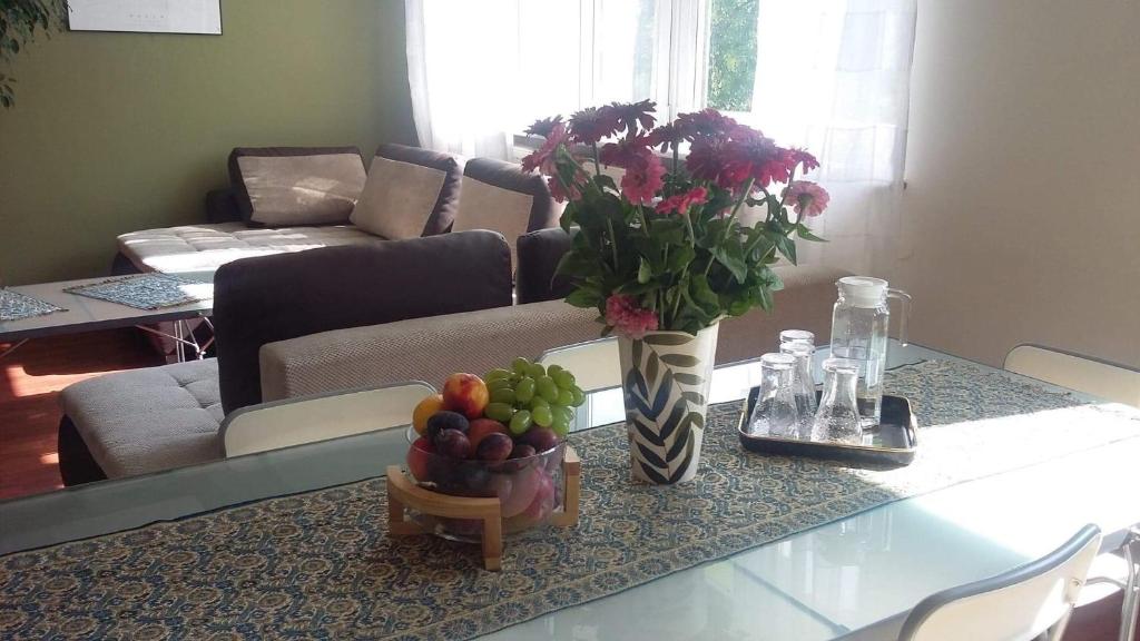stół z wazonem kwiatów i miską owoców w obiekcie Apartment Leśniczówka w Radomiu