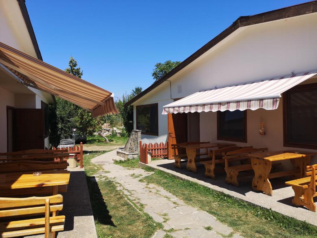 a restaurant with wooden tables and benches next to a building at Стаи за гости АЯКС Guest rooms AJAX in Kranevo
