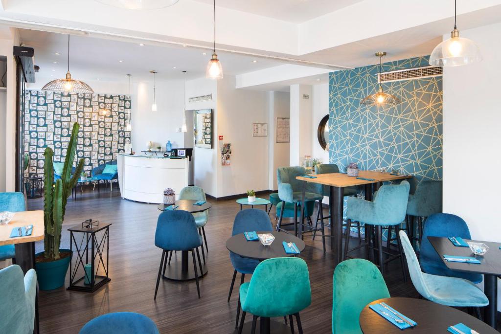 - un restaurant avec des tables et des chaises bleues dans une pièce dans l'établissement Hôtel Relais Acropolis, à Nice