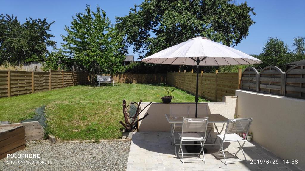 a table and chairs under an umbrella in a backyard at Cute Gite family Aucey Mont Saint Michel in Aucey-la-Plaine