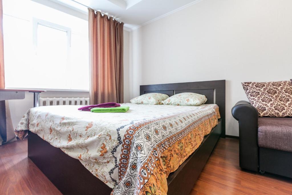 a bedroom with a bed with a blanket and a chair at Центр! Красноармейский 69б-13 in Barnaul